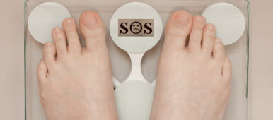 Female Legs On The Scales, The Word Sos On The Display
